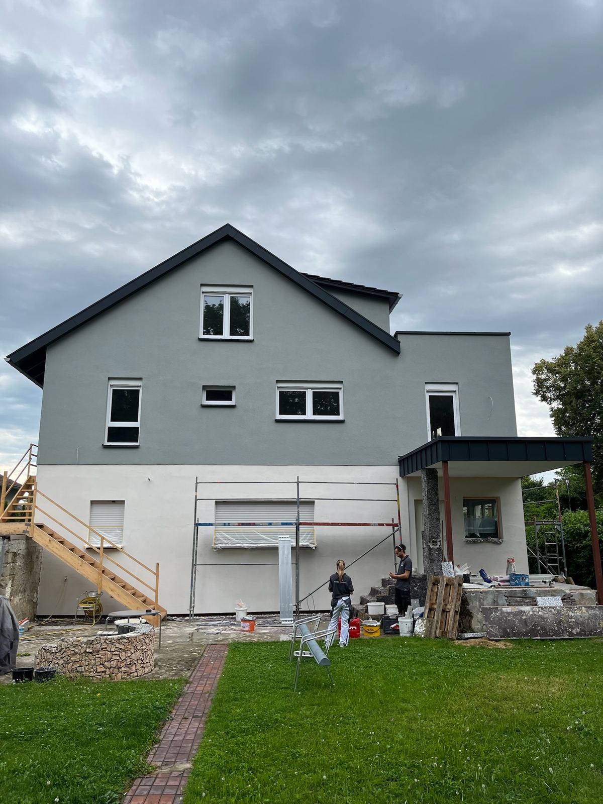 Fertig sanierte Fassade eines Einfamilienhauses mit grauem Oberputz und dunklem Sockel